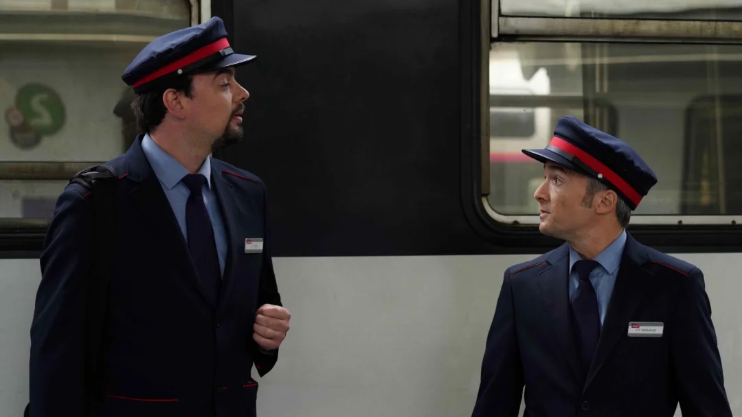 Deux contrôleurs en uniforme face à face sur un quai.