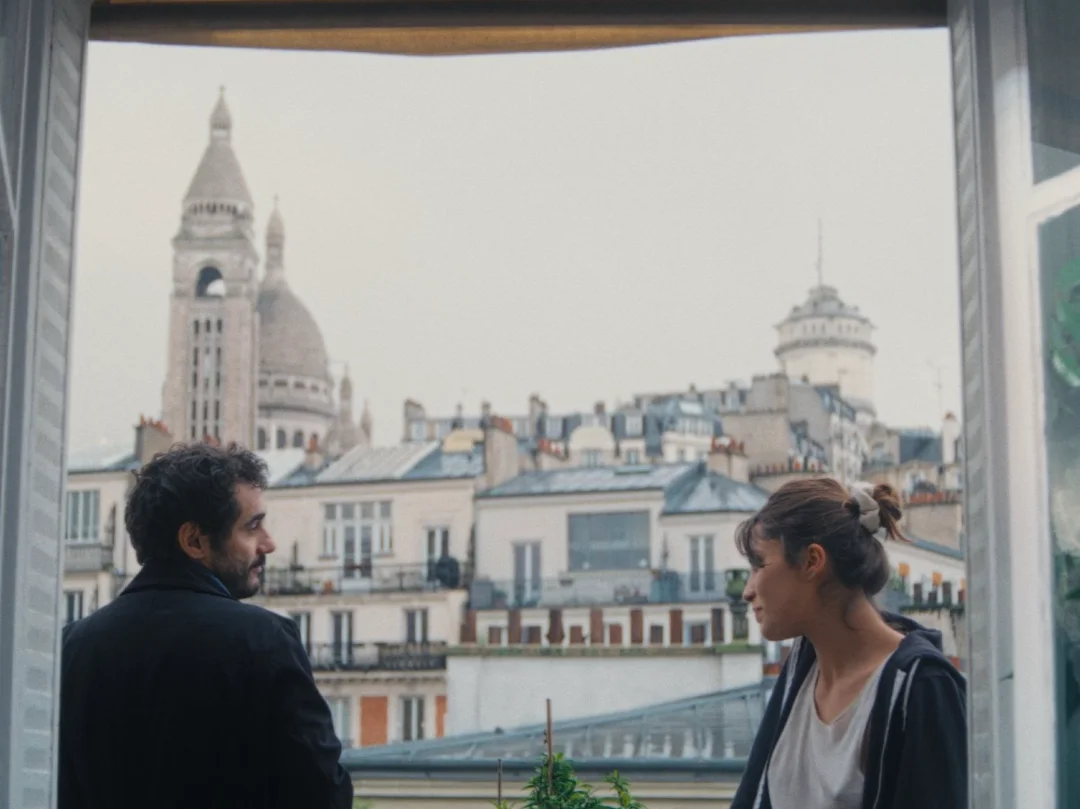 Un homme et une femme à une fenêtre qui donne sur le Sacré-Cœur.